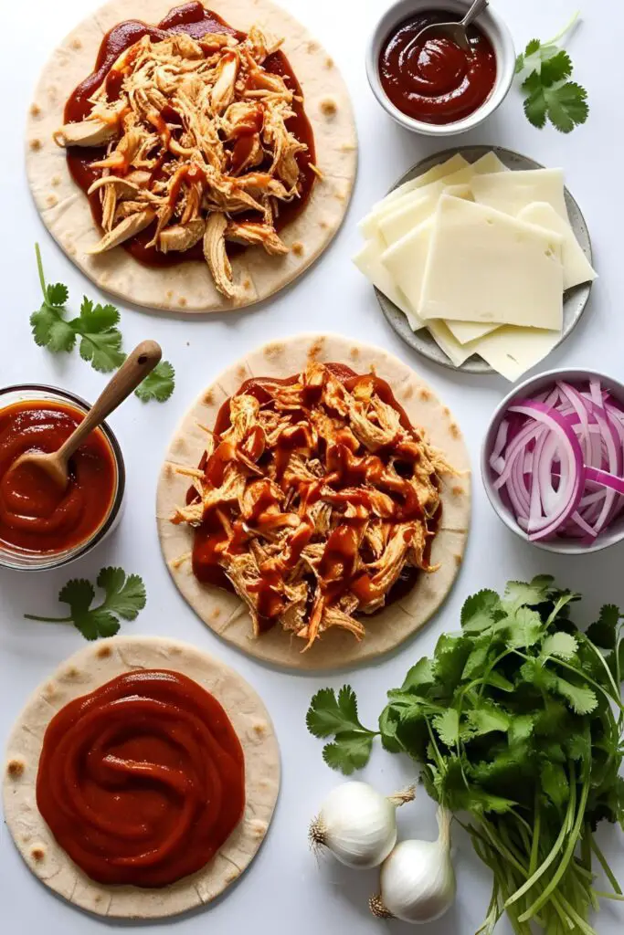 "Sliced BBQ Chicken Flatbread Pizza with red onions and cilantro on a baking sheet"