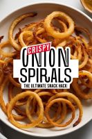 A plate of golden-brown onion spirals served with a dipping sauce