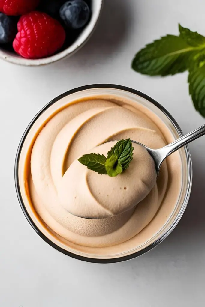 Overhead shot of chocolate mousse in a glass, garnished with fresh berries and mint leaves.