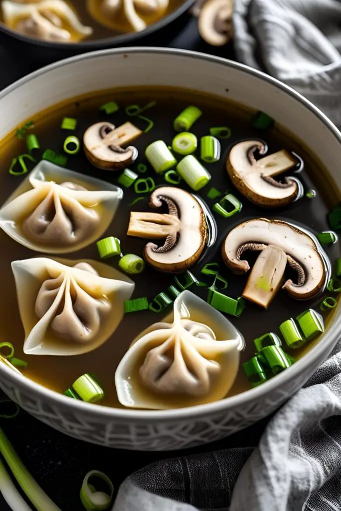  Close-up of steaming mushroom wonton soup with red chili oil drizzle and chopped scallions.