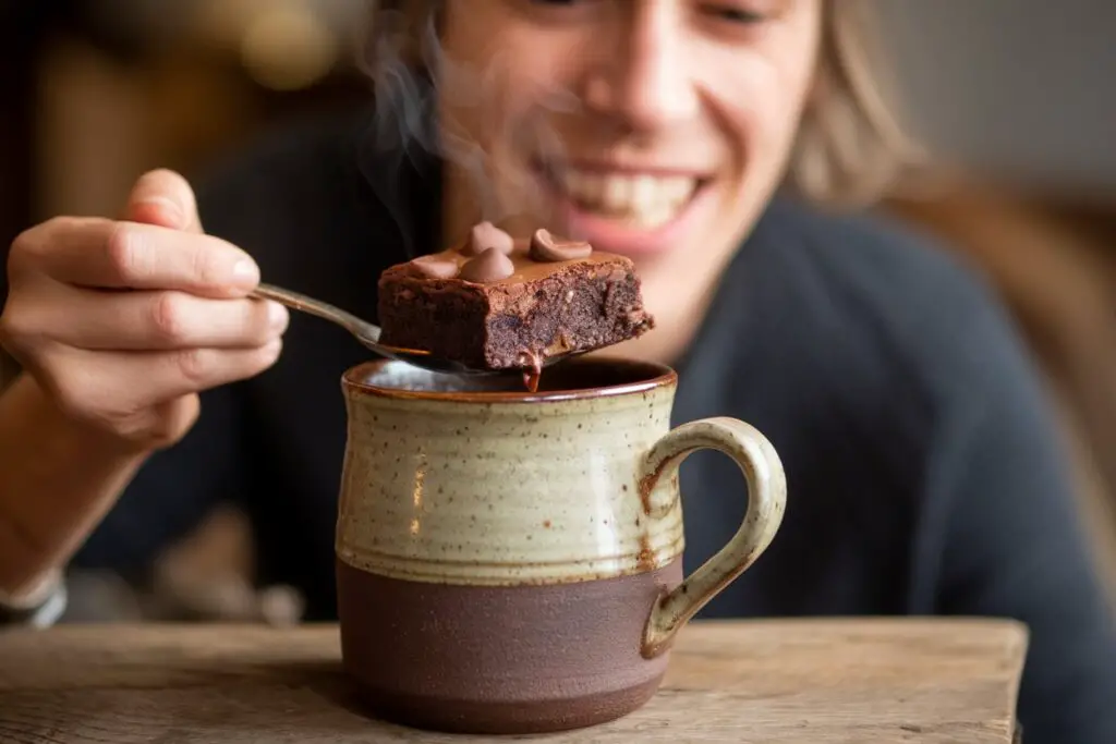 Happy person enjoying a warm brownie in a mug
